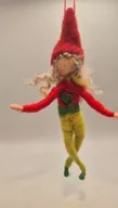 Gefilzte Wichtelfigur mit roter Zipfelmütze, blonden Locken und grün-gelber Kleidung, an einem Faden hängend.