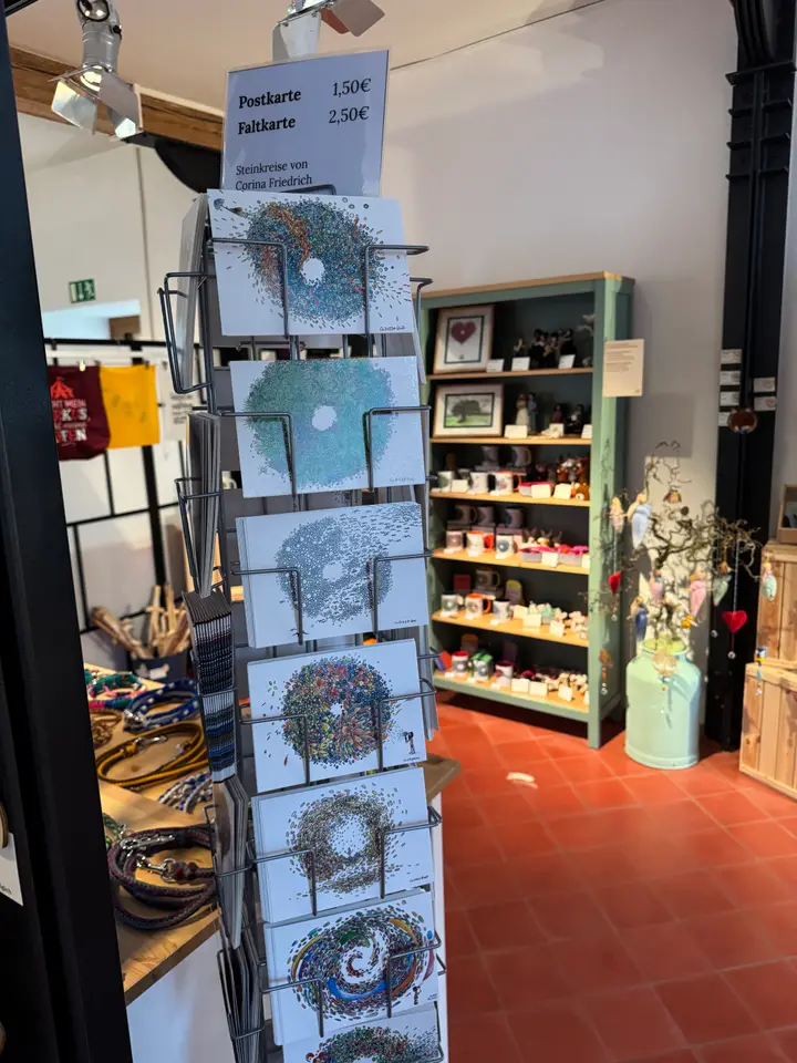 Postkartenständer im Regionalladen Gedern mit den „Steinkreis“-Motiven von Corina Friedrich, daneben das Preisschild für Post- und Faltkarten